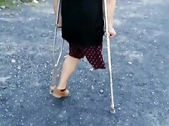 'Amputee Latin guy walking around with crutches in a sunny day'